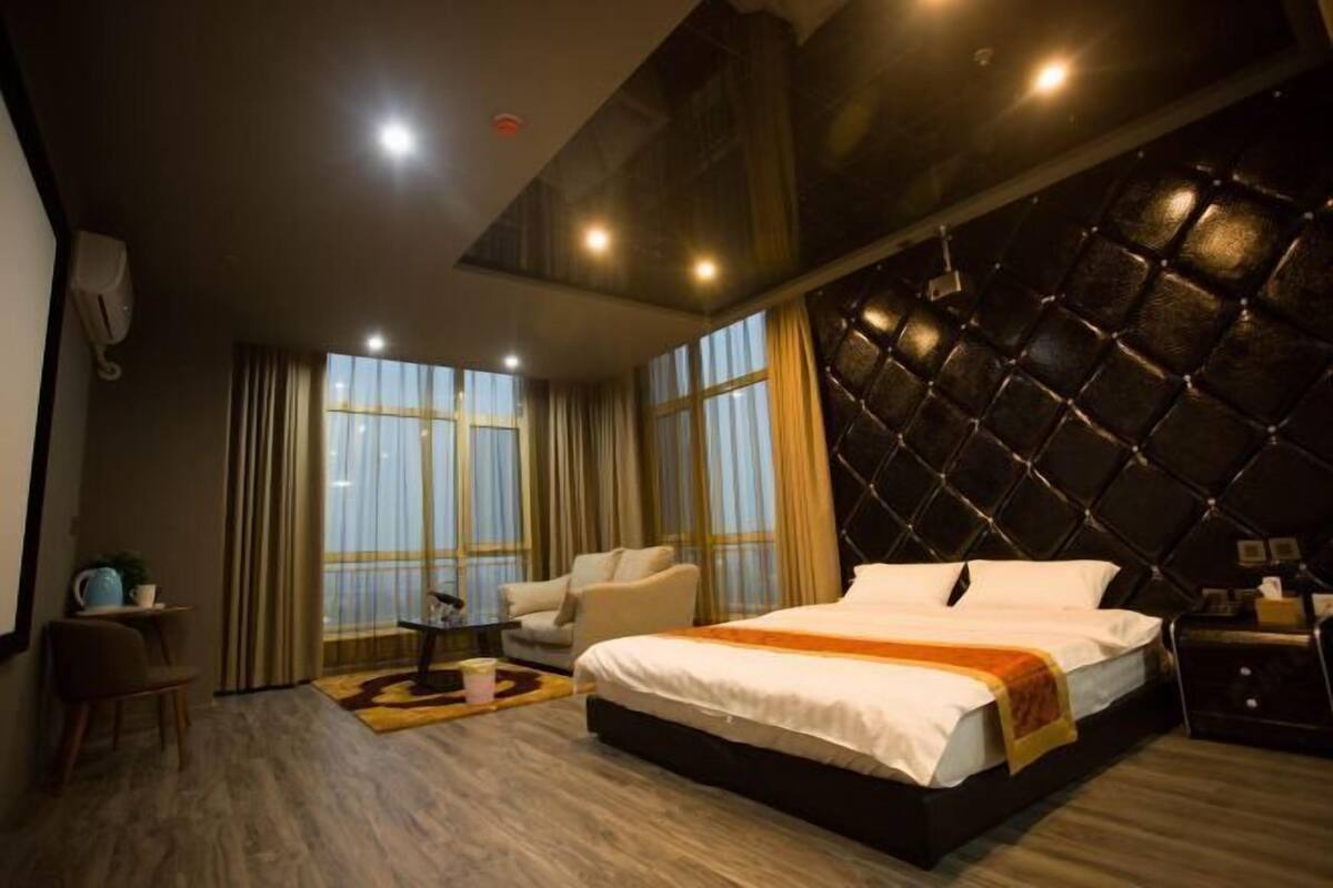 Una habitación de hotel moderna con una cama grande, un sofá, una mesita y una decoración de pared.