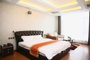 A modern hotel room with a large bed, a bedside table, a chair, and a view of the outdoors.