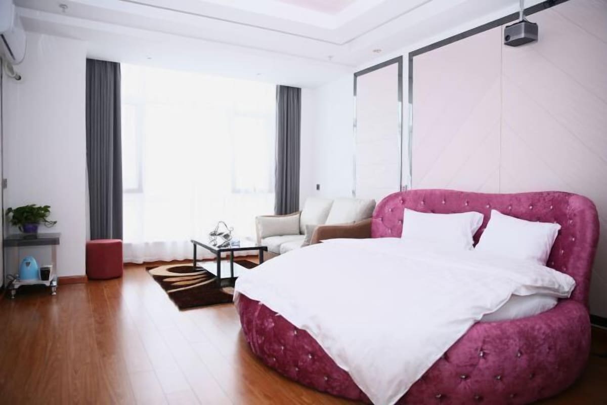 Un dormitorio moderno con una cama grande, un sofá y una mesita.