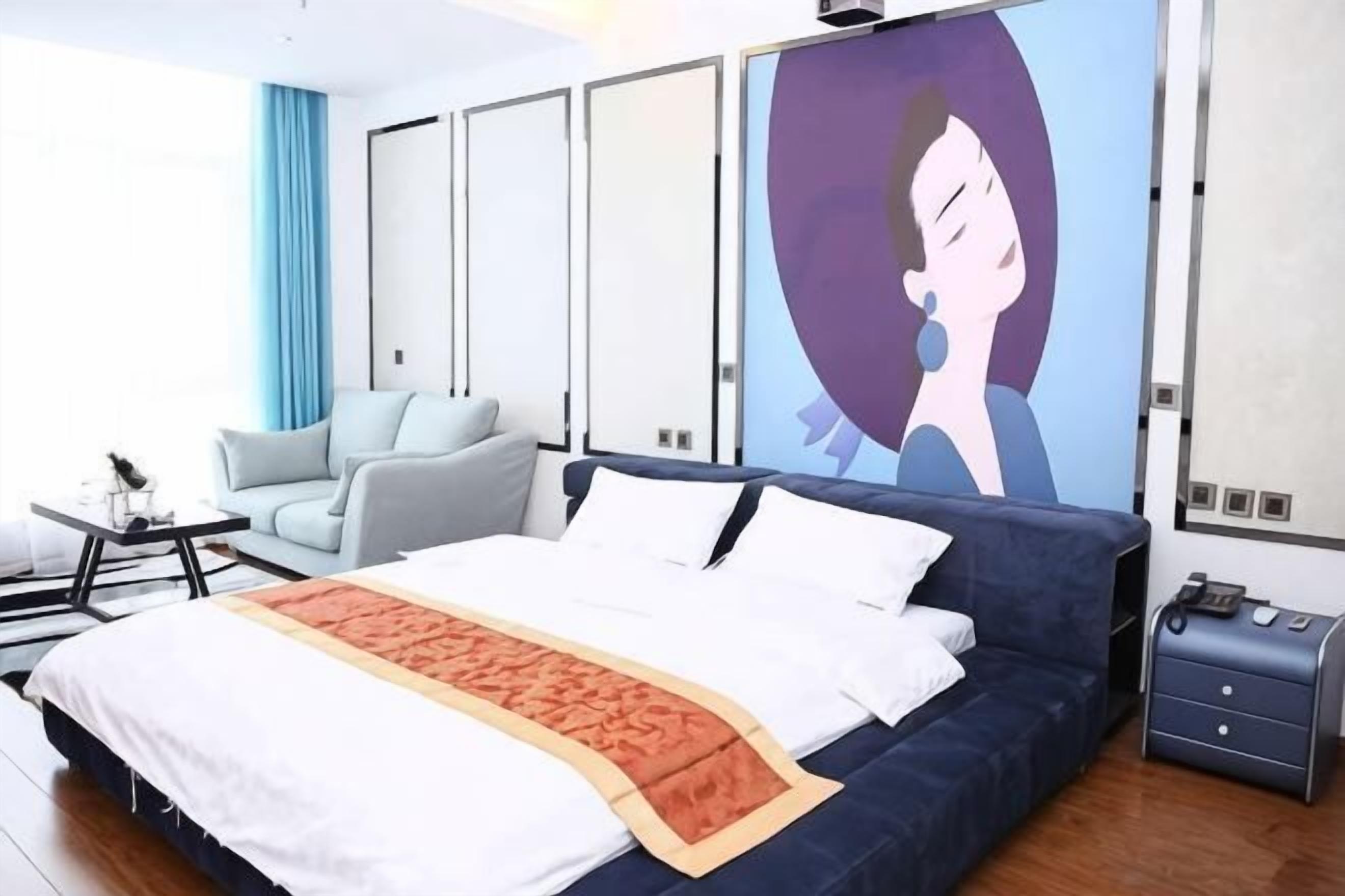 Een moderne hotelkamer met een groot bed, een bank, een bureau en een televisie aan de muur.