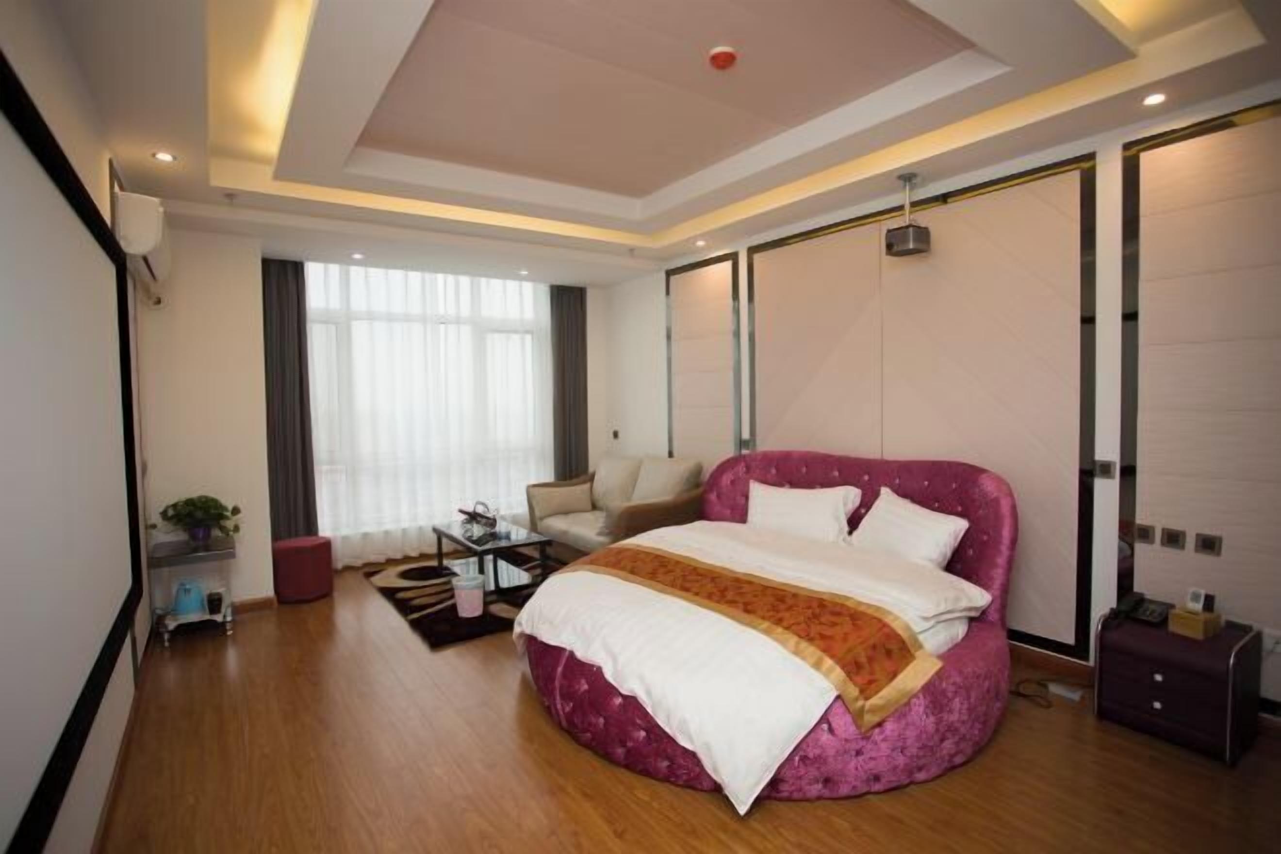 A modern bedroom with a large bed, a sofa, and a small table.