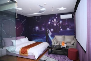 Un dormitorio con cama, sofá, mesa de centro y televisor.