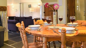 A dining area with a round wooden table, chairs, and wine glasses.