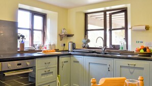 A kitchen with a built-in oven, a sink, and a window with blinds.