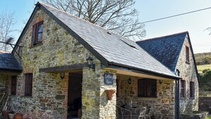 A stone building with a sign reading 'Grother's Barn,' a patio with chairs, and a stone wall.