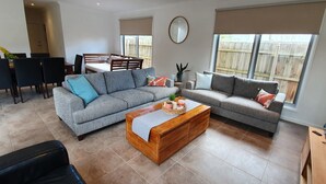 Un salon avec deux canapés gris, une table basse en bois et un coin repas comprenant une table et des chaises.