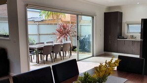 Une cuisine moderne avec des meubles de couleur sombre, une petite fenêtre et un coin repas comprenant une table et des chaises.