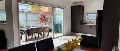Een moderne keuken met donkere kastjes, een klein raam en een eethoek met een tafel en stoelen.