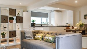 A modern living room with a sofa, a coffee table, and a kitchen in the background. - 3 bedroom accommodation in Skipton (Skipton)