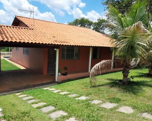 Enjoy a tropical ambiance in this single-story retreat with a red-tiled roof and porch area, surrounded by a well-maintained lawn and palm tree.