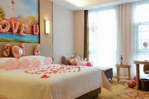 A hotel room with a large bed, a painting on the wall, and a window with curtains.