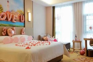 Habitación de hotel con una cama grande, un cuadro en la pared y una ventana con cortinas.