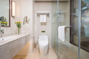 A modern bathroom with a glass shower enclosure, a marble sink, and a toilet. - Baiyunbao International Hotel (Wangcang)
