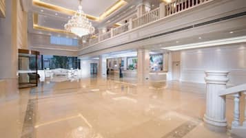 A spacious lobby with a high ceiling, a grand chandelier, and a second-floor balcony.