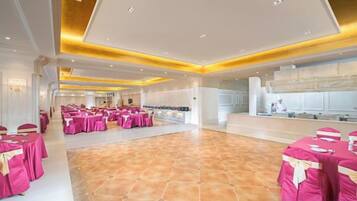 A spacious hall with multiple round tables covered in pink tablecloths, arranged for a gathering.