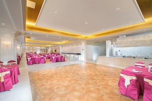 A spacious hall with multiple round tables covered in pink tablecloths, arranged for a gathering.