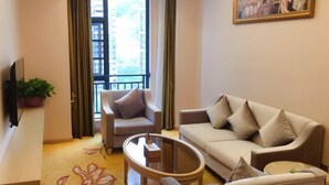 A modern living room with a sofa, armchairs, a coffee table, and a TV. - Baiyunbao International Hotel (Wangcang)