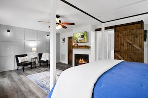 A bedroom with a bed, a fireplace, a ceiling fan, and a wooden door. - 2 Masters + 2 Kitchens + Game Room + Fire Pit + Hot Tub (Blue Ridge)