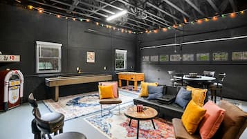A cozy room with a pool table, comfortable seating, and string lights.