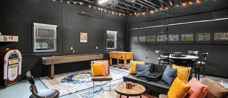 Una habitación acogedora con mesa de billar, asientos cómodos e iluminación ambiental con luces colgantes.