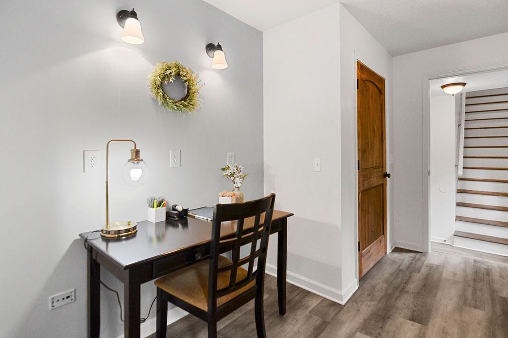 A dining area with a table, chairs, a lamp, and a wall-mounted light fixture.