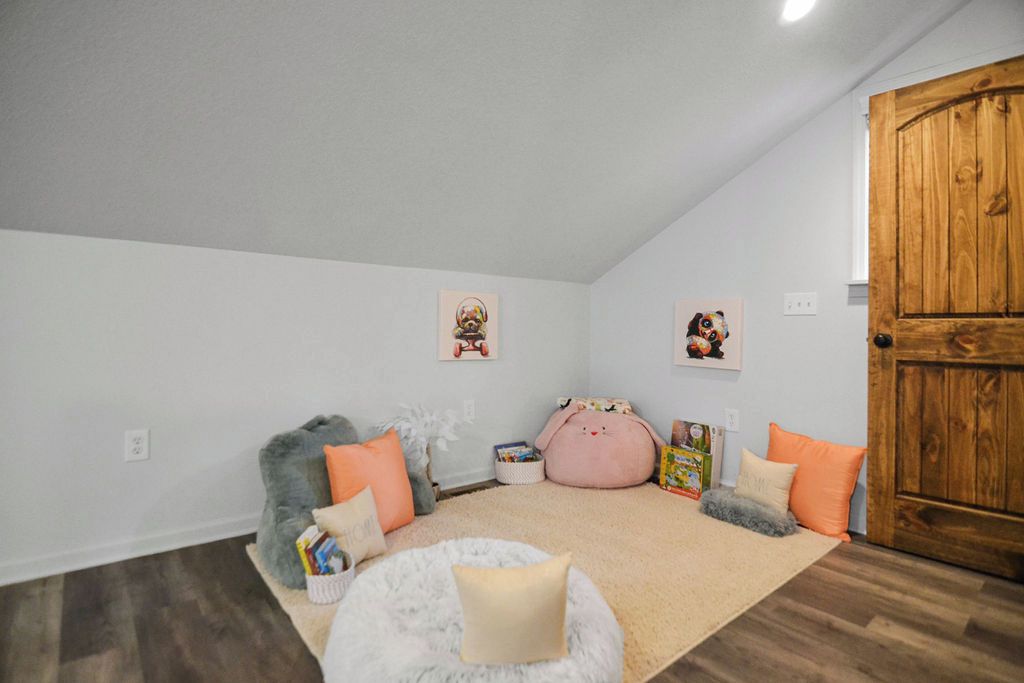 A cozy room with a wooden door, a fluffy rug, and a small round bed with pillows.