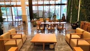 A spacious lobby with a central seating area, large windows, and a green wall.