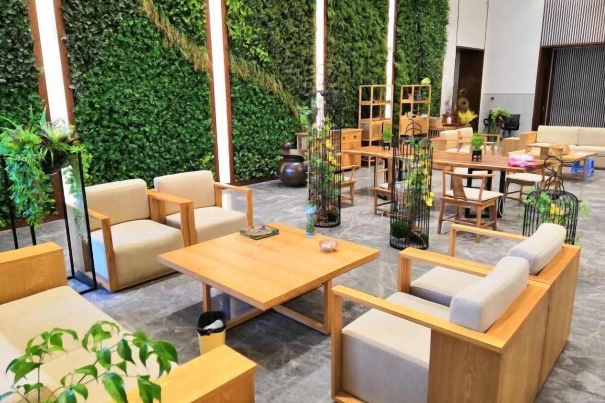 A modern lounge area with wooden furniture, green wall decor, and a variety of seating options.