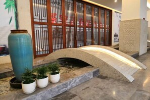 A stone bridge, potted plants, and a decorative wooden screen in a lobby area. - Pristime International Holiday Hotel (Yinjiang)