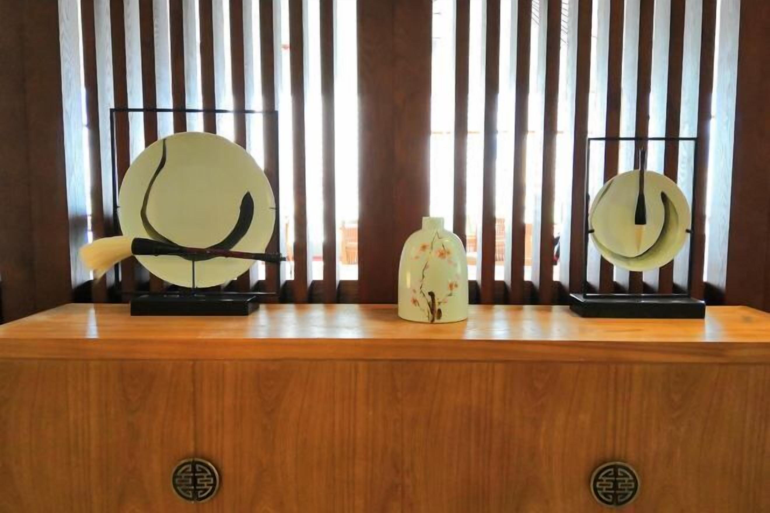 Una barra de madera con dos instrumentos musicales chinos tradicionales, un guqin y una pipa, además de un jarrón decorativo.