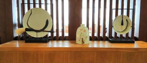 Una barra de madera con dos instrumentos musicales chinos tradicionales, un guqin y una pipa, además de un jarrón decorativo.