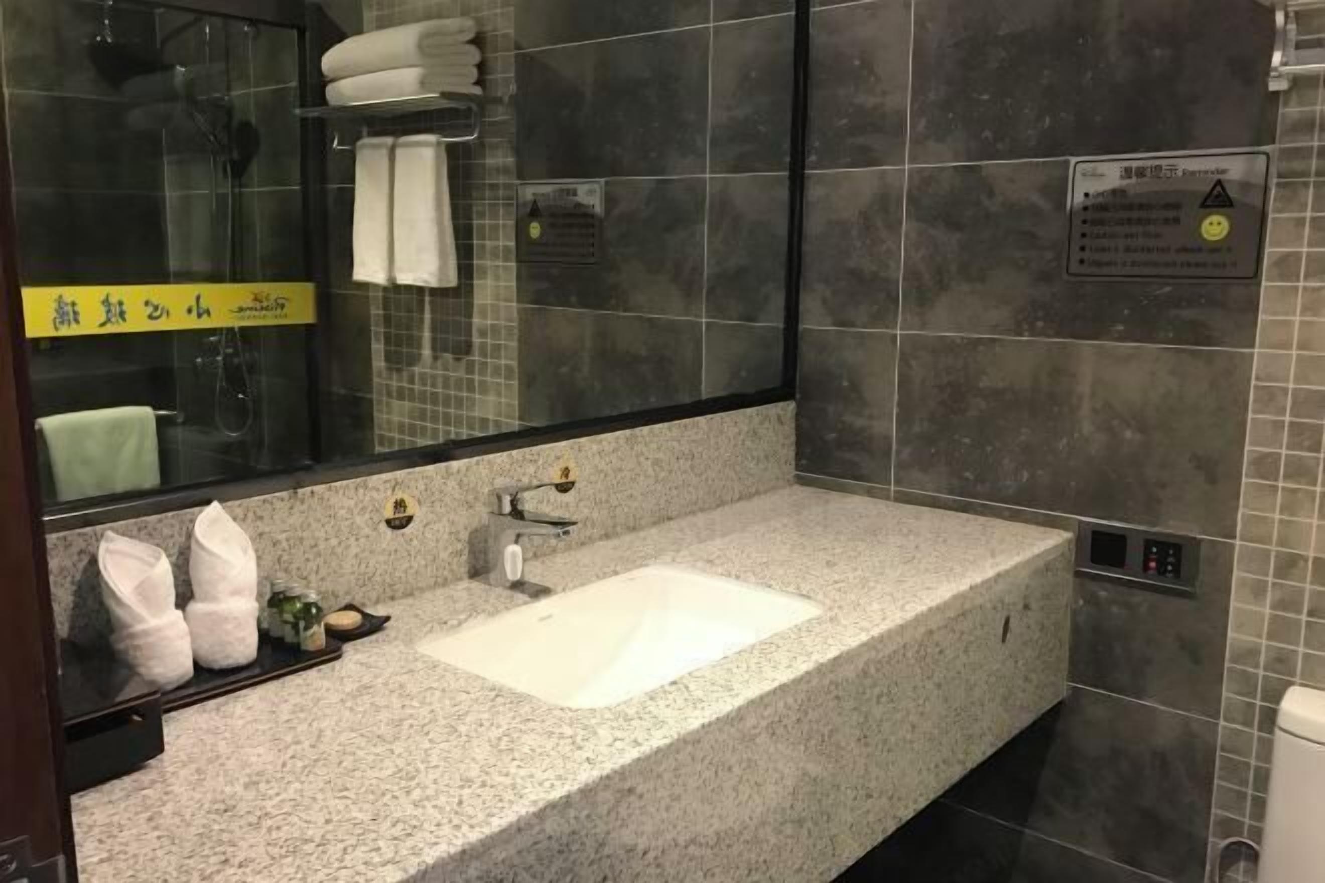 Ein modernes Badezimmer mit Marmorwaschtisch, einer Duschkabine aus Glas und einem Handtuchhalter mit weißen Handtüchern.