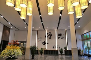 A reception area with a large wall featuring calligraphy, a reception desk, and multiple hanging lamps. - Pristime International Holiday Hotel (Yinjiang)