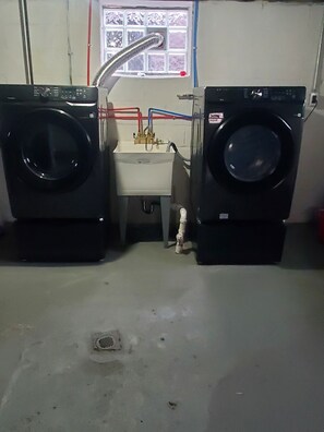 A laundry room with two large front-loading washing machines, a sink, and a window with a view of the outside. - Spacious 4 bedrooms, 6 beds, 2 baths (Detroit)