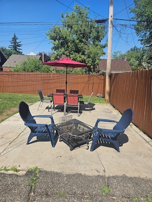A backyard patio with a fire pit, outdoor furniture, and a red umbrella. - Spacious 4 bedrooms, 6 beds, 2 baths (Detroit)