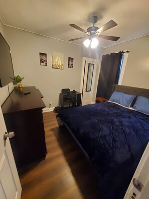 A bedroom with a bed, a desk, a ceiling fan, and a door. - Spacious 4 bedrooms, 6 beds, 2 baths (Detroit)