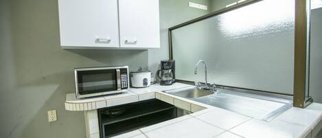 A compact kitchen with a microwave, coffee maker, and sink.