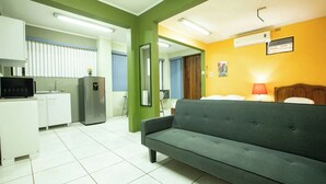 A compact living space with a kitchenette, a sofa, a small table, and a bed. - Coati Arenal Lodge (La Fortuna)