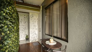A wooden table with a white placemat and a dessert on it, positioned next to a window with a curtain. - Coati Arenal Lodge (La Fortuna)