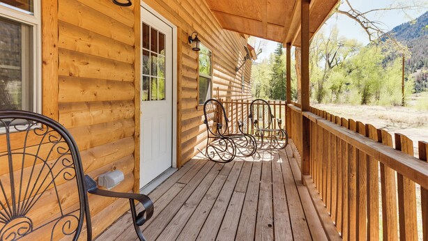 A wooden cabin with a porch, a door, and two chairs. - Cottonwood Cove (South Fork)
