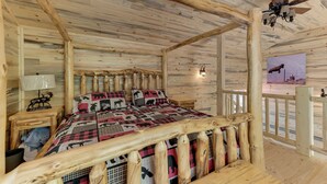 A log cabin bedroom with a bed, wooden headboard, and a ceiling fan. - Cottonwood Cove (South Fork)