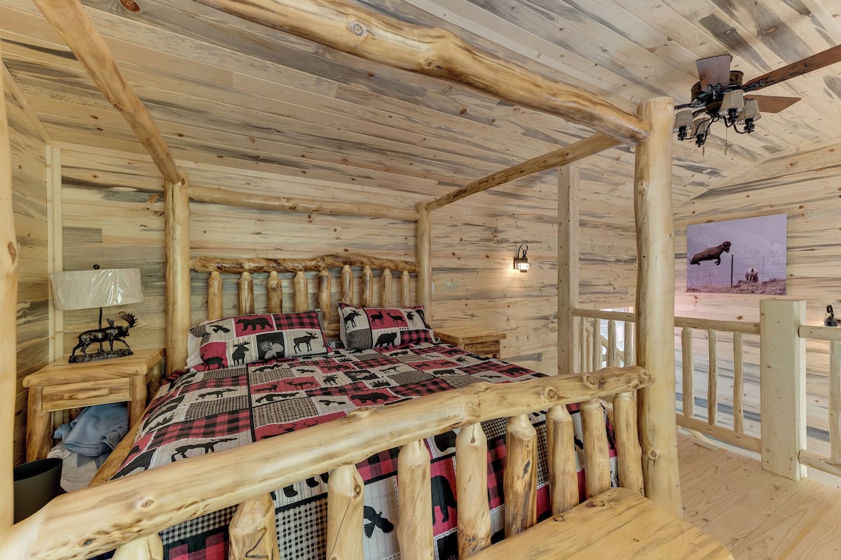Ein Schlafzimmer in einer Blockhütte mit einem Bett, einem Holzkopfende und einem Deckenventilator.
