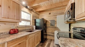 A compact kitchen with wooden cabinetry, a stainless steel refrigerator, a built-in oven, and a granite countertop. - Cottonwood Cove (South Fork)