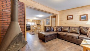 A cozy living room with a large fireplace, a leather sectional sofa, and a wooden floor. - Cottonwood Cove (South Fork)