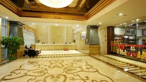 A hotel lobby with a reception desk, a large chandelier, and a patterned floor. - JI Hotel (Shenzhen)