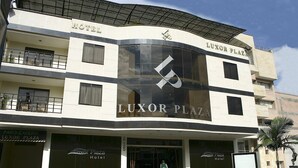 Un hotel con un llamativo letrero 'LUXOR PLAZA', varios balcones y ventanas amplias.