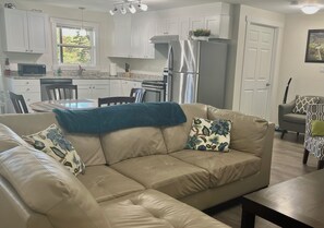 Een moderne keuken met witte kasten, een roestvrijstalen koelkast en een eethoek met een tafel en stoelen.