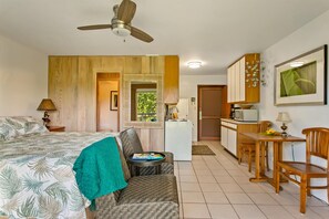 A compact hotel room with a bed, a small seating area, a kitchenette, and a dining table. - Beautiful 2nd floor ocean view studio (Koloa)