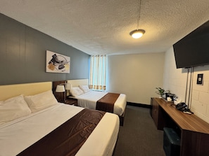 A hotel room with two beds, a desk, a television, and a window with curtains. - Grand Royal Legacy (Winnipeg)