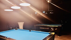 Una mesa de billar en una habitación con poca luz e iluminación desde el techo.